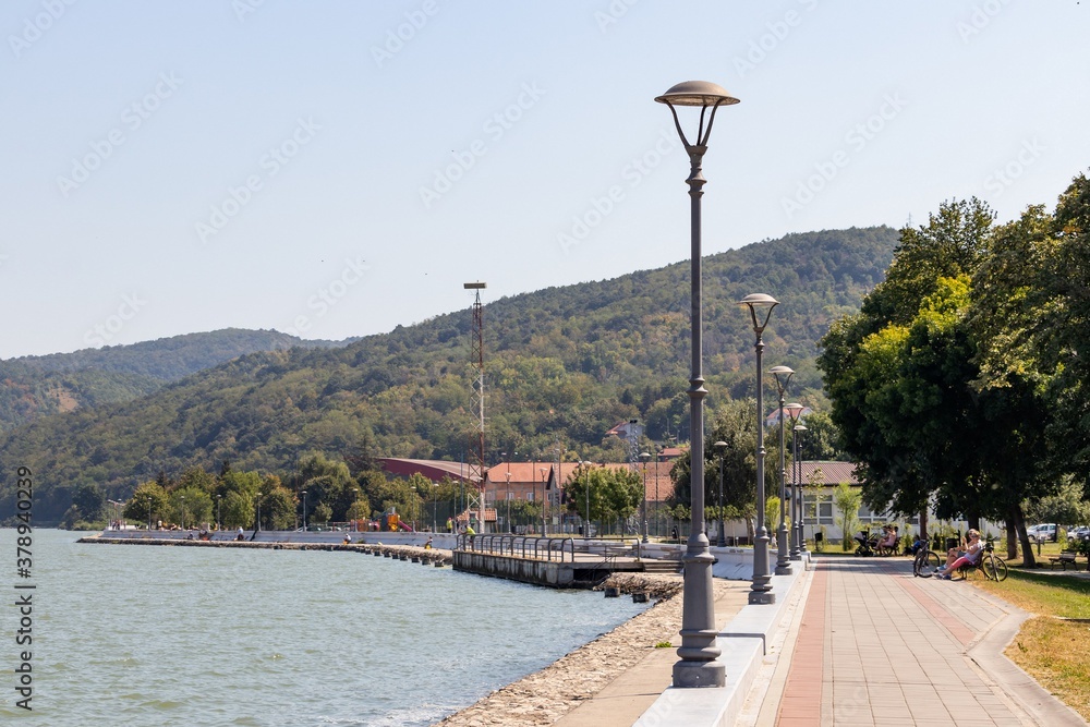 Landscape: river embankment with a promenade against the backdrop of a mountain on a sunny day