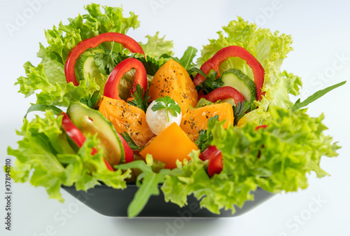 Vegetable salad is a low-calorie cold vegetarian snack. The dish contains the following ingredients: mozzarella, tomatoes, bell pepper, cucumber and lettuce. photo