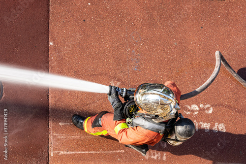 French firefighter in helmet with fire hose shot with top-down view