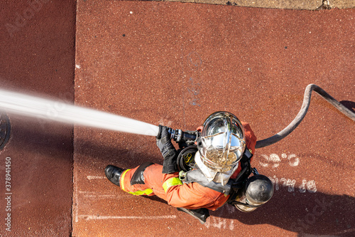 French firefighter in helmet with fire hose shot with top-down view
