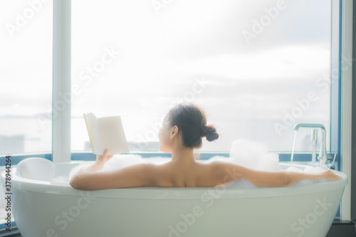 Portrait beautiful young asian woman read book in white bathtub