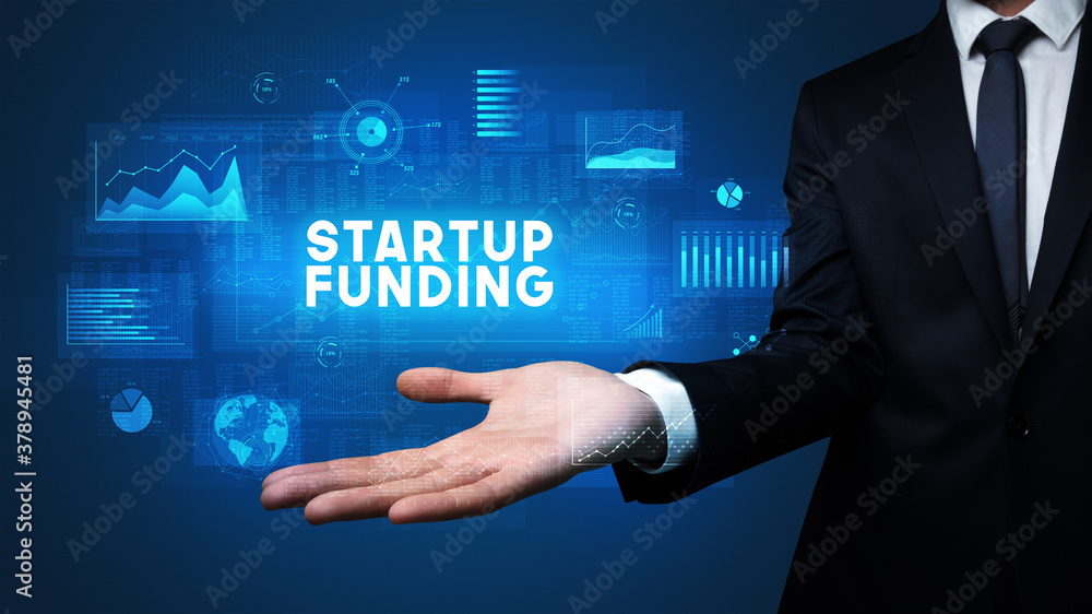 Hand of Businessman holding STARTUP FUNDING inscription, business success concept Hand of Businessman holding STARTUP FUNDING inscription, business success concept