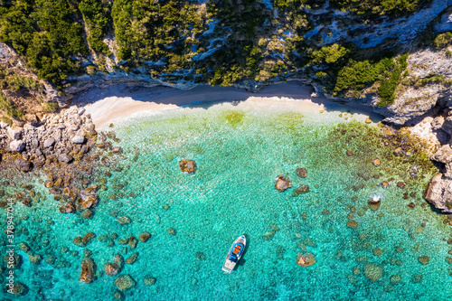 A small, secluded beach at Lixouri on the island of Kefalonia, Greece, with a fishing boat over crystal clear, turquoise sea