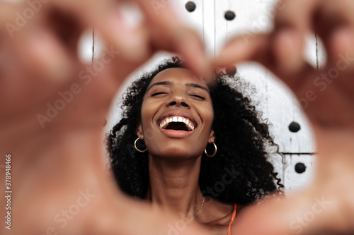 Tablou pe pânză Cheerful ethnic woman with heart gesture