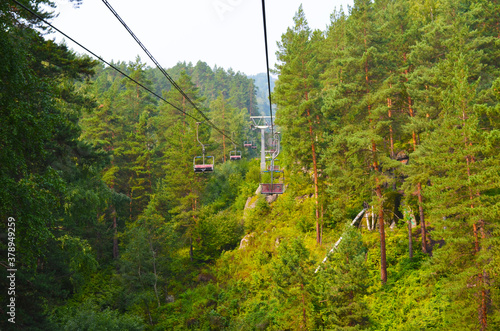 Suspended cable car in the summer forest. Climb the mountain. Nature