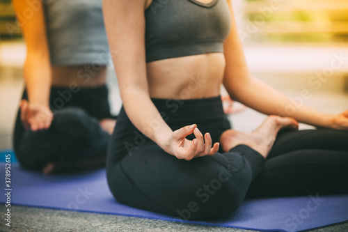 Young Women practicing yoga together and sitting in the lotus pose
