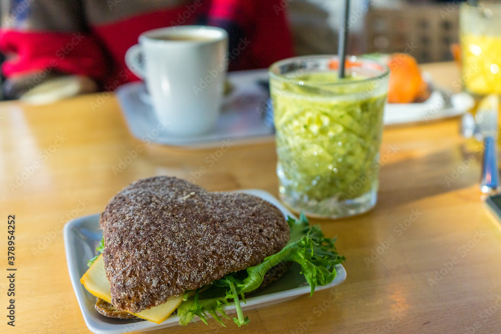Rye bread sandwich with salad and cheese, green smoothie and coffee for breakfast