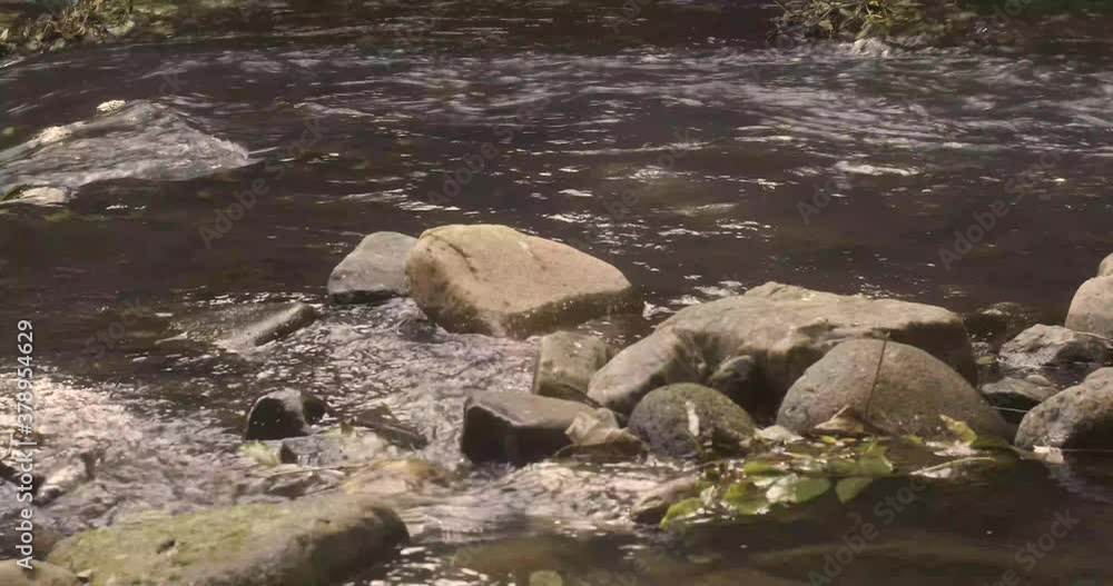 Urban river with water flowing around and inbetween rocks Urban river with water flowing around and inbetween rocks