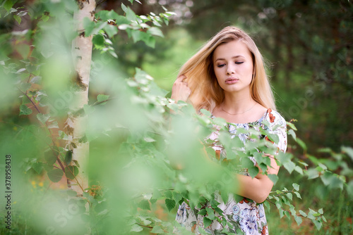 Charming girl in nature near a birch tree