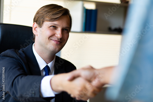 Young caucasian businessman shaking hands to deal business
