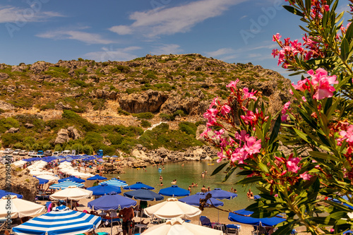 Obraz na płótnie Rhodes, Greece - July 5, 2019 - In a bay on the island of Rhodes, holidaymakers relax under parasols w salonie
