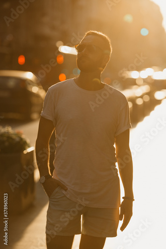 A man in sunglasses is sightseeing of Valencia in rays of the sunset.