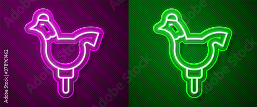Glowing neon line Candy cockerel lollipop on a stick icon isolated on purple and green background. Vector.