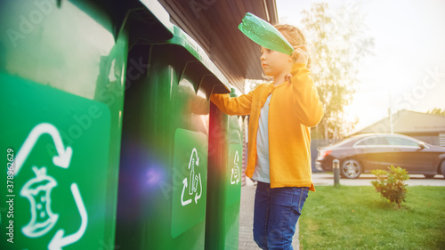 Fotografie Young Girl is Throwing Away an Empty Plastic Bottle into a Trash Bin