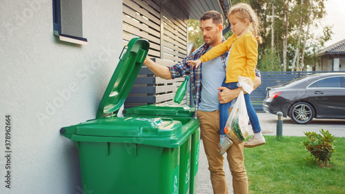 Father Holding a Young Girl and Throw Away an Empty Bottle and Food Waste into the Trash. They Use Correct Garbage Bins Because This Family is Sorting Waste and Helping the Environment.