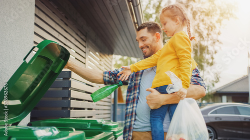 Tableau sur toile Father Holding a Young Girl and Throw Away an Empty Bottle and Food Waste into the Trash