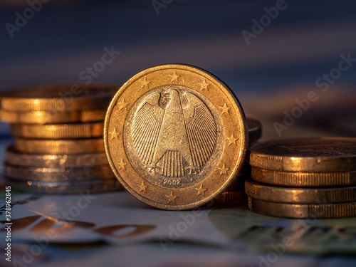 Close up view on German one Euro coin with euro coin stacks on one hundret euro bill photo