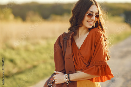 Woman in a summer field. Brunette in a yellow skirt. Girl on a sunset background.