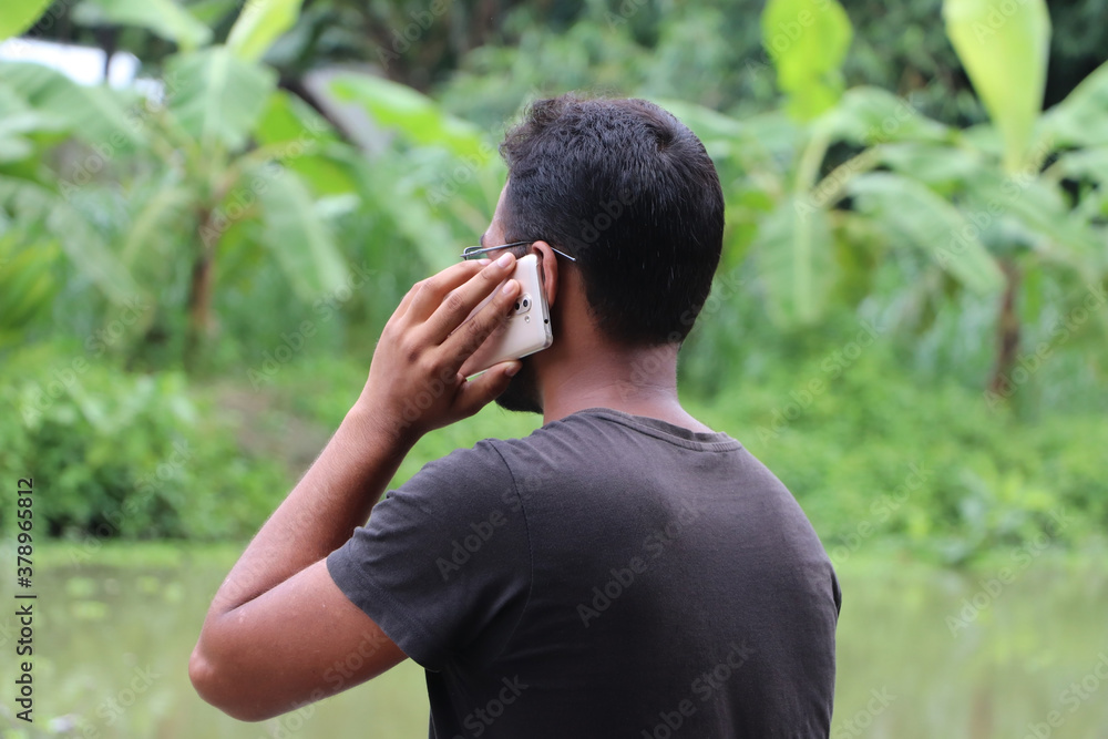 Back side view of a young businessman talking on mobile phone. Talking about new project. Working outside concept Back side view of a young businessman talking on mobile phone. Talking about new project. Working outside concept