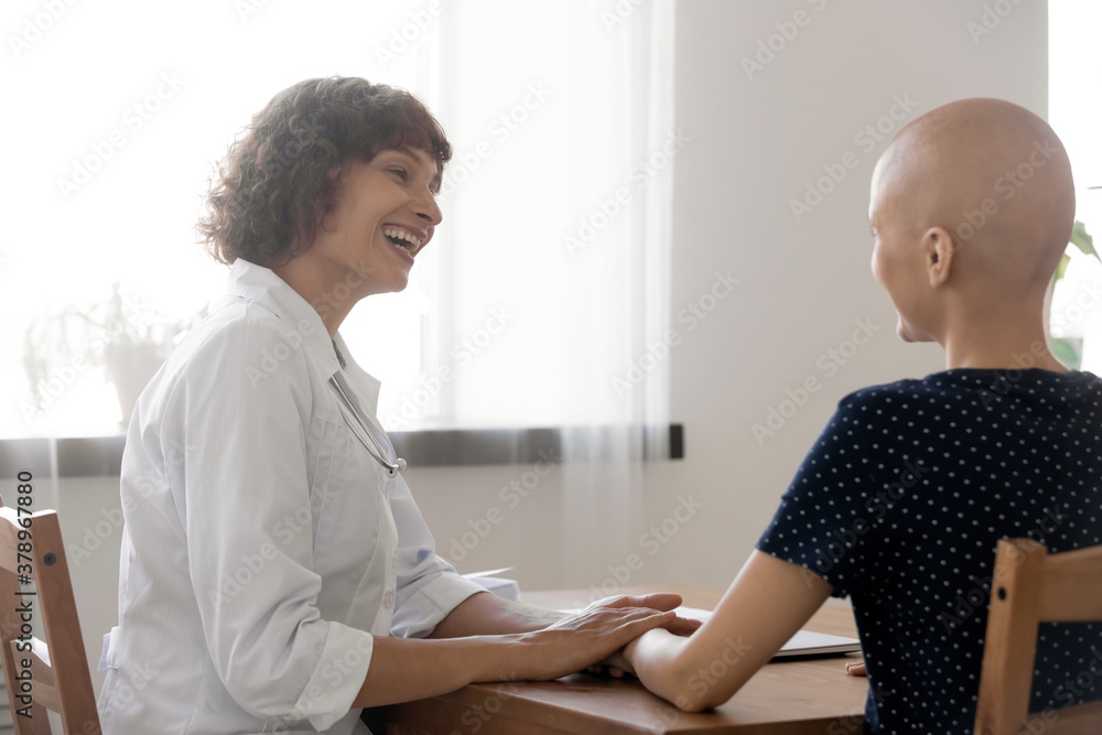 Happy doctor support hairless female patient suffering from cancer, talk at consultation at hospital. Smiling nurse show empathy comfort speaking with woman with oncology. Remission concept. Happy doctor support hairless female patient suffering from cancer, talk at consultation at hospital. Smiling nurse show empathy comfort speaking with woman with oncology. Remission concept.