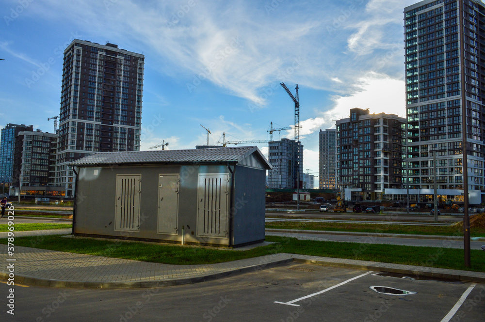 electrical house with power lines. concrete house with insulation and air conditioning for electricity shields. against the background of glass houses of a new residential complex electrical house with power lines. concrete house with insulation and air conditioning for electricity shields. against the background of glass houses of a new residential complex