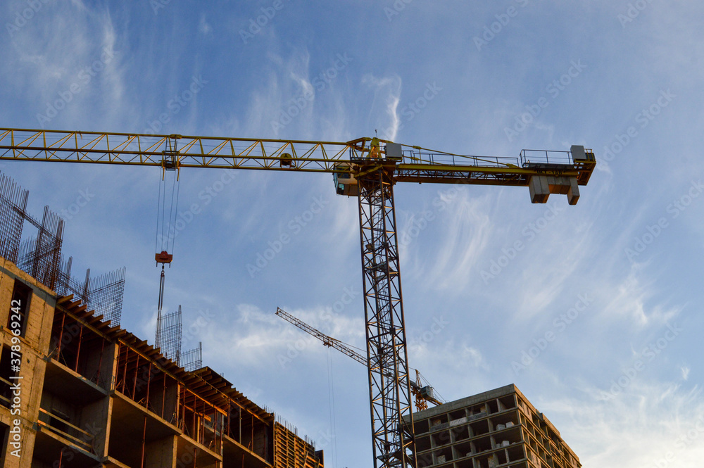 construction of a new residential building from concrete blocks. crane builds a new floor, pulls blocks. metal pins protrude from concrete blocks. the second crane builds a house nearby
