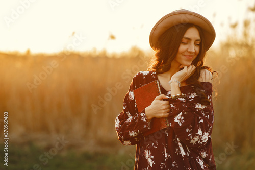 Woman in a summer field. Brunette in a yellow skirt. Girl on a sunset background. photo