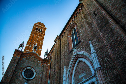 Torre de ladrillo en iglesia con detalle de entrada en  fachada y rosetón gótico photo