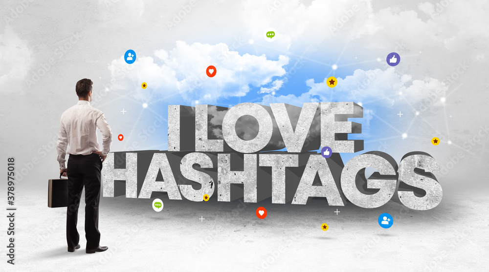 Young businessman standing in front of I LOVE HASHTAGS inscription, social media concept Young businessman standing in front of I LOVE HASHTAGS inscription, social media concept