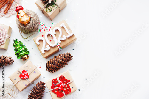 Christmas present on white background with copy space. New Year 2021 gifts wrapped in craft paper with decorations. Winter holiday symbols.