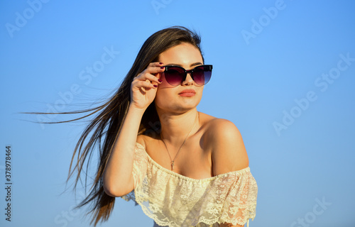 spring mood. sexy girl with brunette hair on sky background. perfect sunset or sunrise. pretty woman wear sunglasses. female summer fashion. sensual beauty in white dress outdoor. Facial care