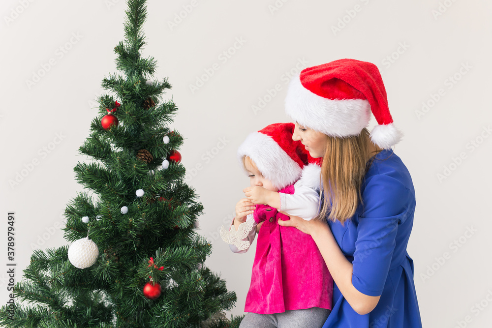 Christmas concept - mother and her little daughter with Christmas tree at living room Christmas concept - mother and her little daughter with Christmas tree at living room