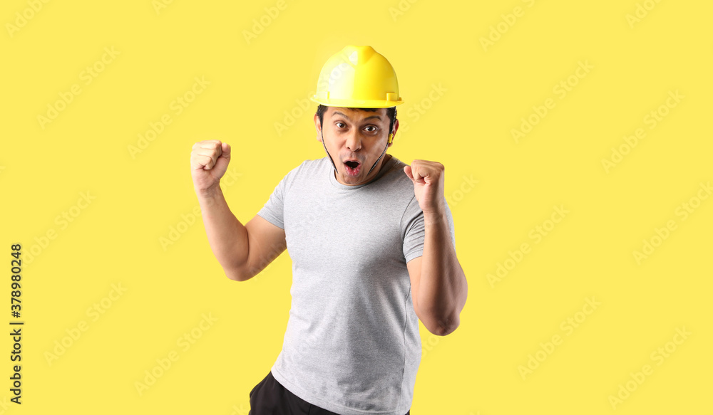 Asian man Industry worker or engineer working an architect builder Happy excited raising his fists on yellow background in studio With copy space. Asian man Industry worker or engineer working an architect builder Happy excited raising his fists on yellow background in studio With copy space.