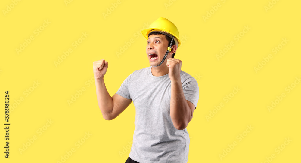 Asian man Industry worker or engineer working an architect builder Happy excited raising his fists on yellow background in studio With copy space. Asian man Industry worker or engineer working an architect builder Happy excited raising his fists on yellow background in studio With copy space.