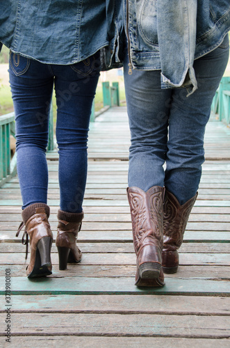 People wear jeans to wear boots walking on a wooden bridge. 