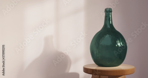 Empty green demijohn bottle in empty room, window shadow cast on wall. 3d rendering. photo