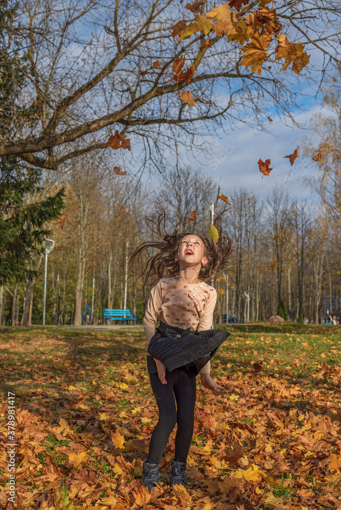 A cheerful girl throws up fallen leaves in the park. A cheerful girl throws up fallen leaves in the park.