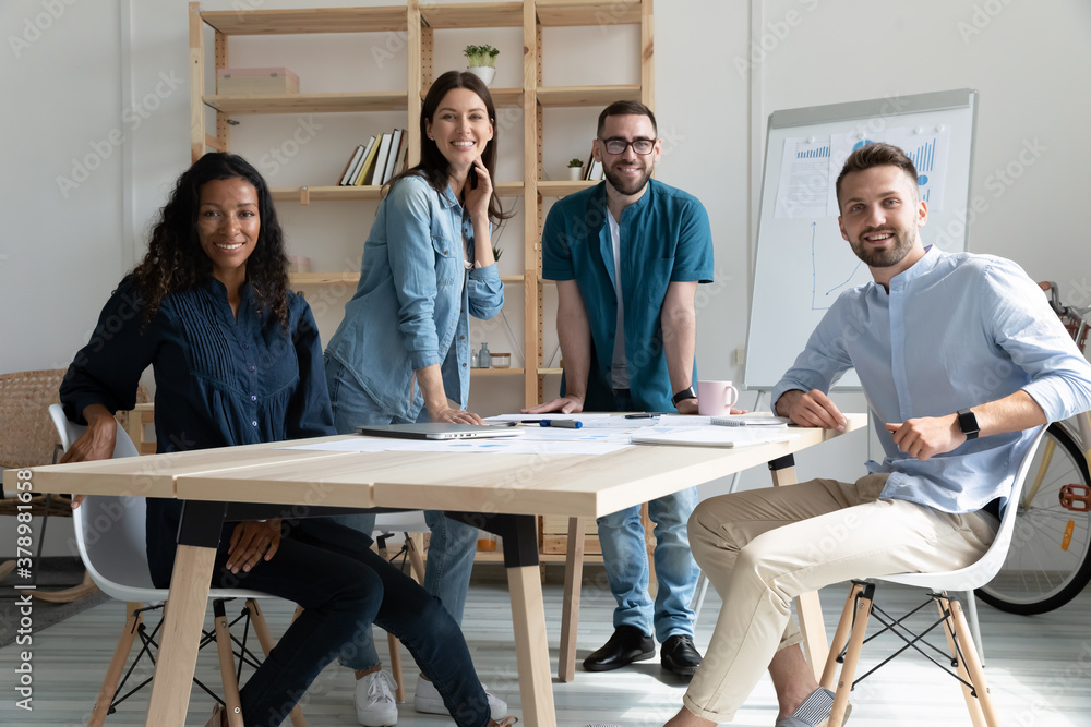 © fizkes - Smiling diverse employees colleagues group portrait in modern boardroom, business people working on financial project statistics together, posing for photo in office, looking at camera