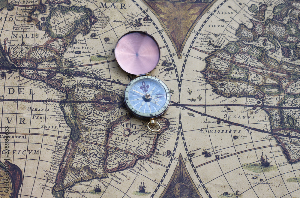 Classic round compass on background of old vintage map of world as symbol of tourism with map and compass, travel with with map and compass and outdoor activities with with map and compass