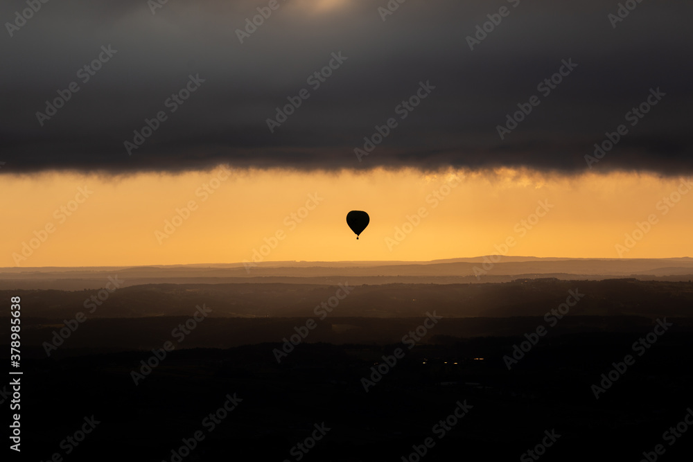 In the low sun of the morning a balloon gets close to the cloud cover 