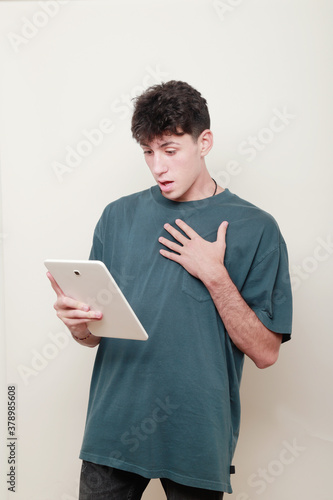 Quadro su tela chico vestido casual con cara de asombro viendo la pantalla de su tablet