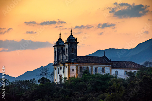 Ancient and historic church on top of the hill during sunset in the city of Ouro Preto in Minas Gerais, Brazil with the mountains behind