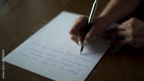 Kuchl / Austria - August 22 2019: Female hands writing letter on white paper on wooden table close up. love vintage letter. Brides vow. Wedding preparations. Slow motion.