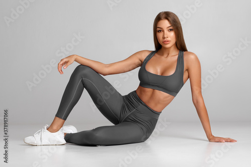 Sexy fitness woman. Beautiful athletic girl, isolated on the gray  background фотография Stock