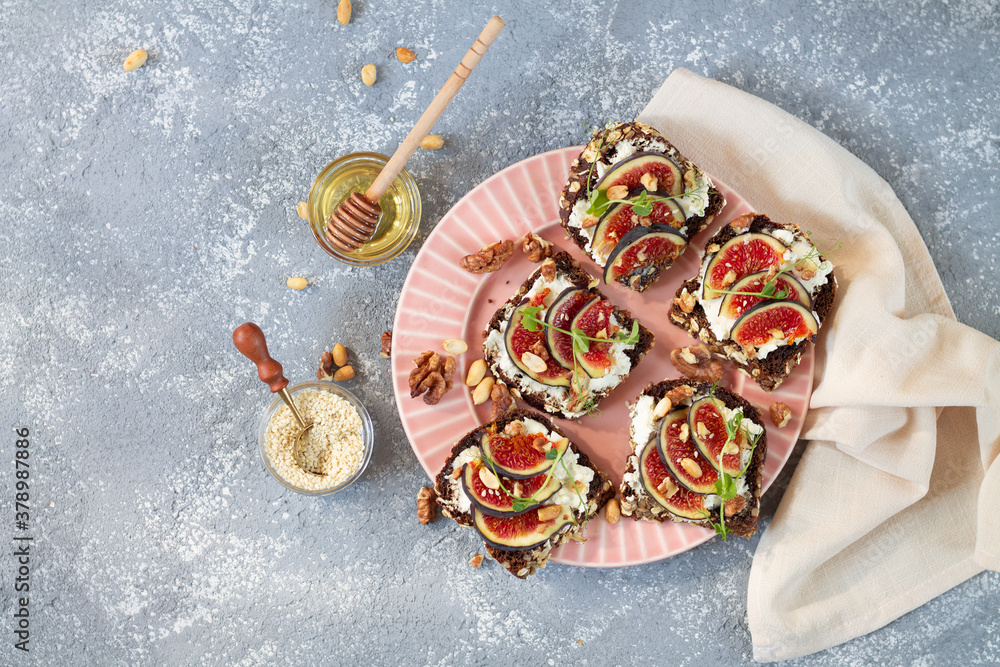 Plate of healthy appetizers. Bruschettas with figs, cheese, sesame, huts and honey