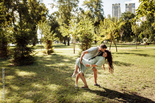Overjoyed couple dancing at the park, loving husband hold in arms beautiful wife, pretty woman smiling, enjoy happy time together, relaxing, healthy relationship concept © shunevich