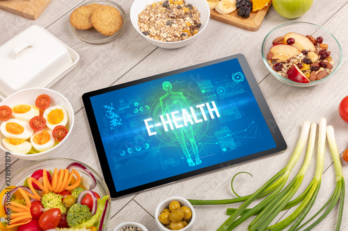 E-HEALTH concept in tablet with fruits, top view