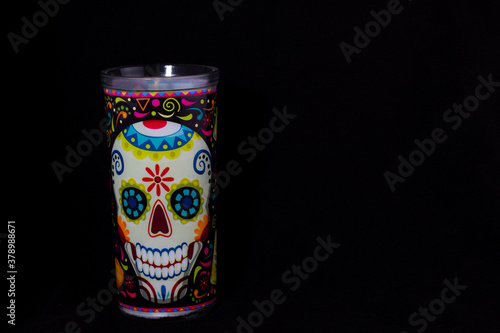 a hand painted day of the dead skull candle on a black background