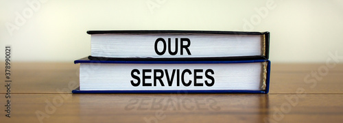 Books with the text 'our services' on beautiful wooden table, white background. Business concept.