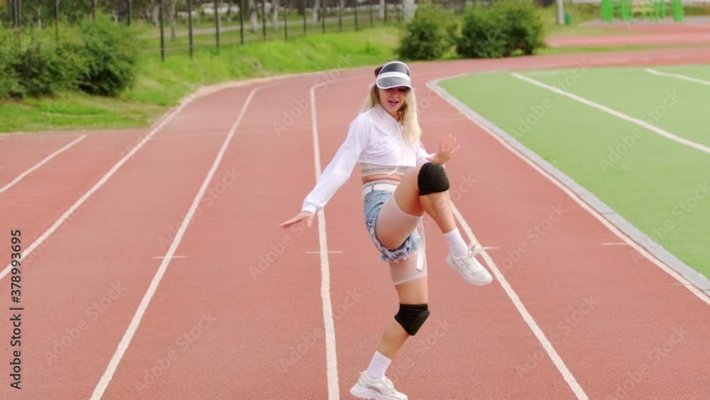 Young beautiful blonde woman dancing dancehall with twerking elements on stadium running track. Slow motion Young beautiful blonde woman dancing dancehall with twerking elements on stadium running track. Slow motion